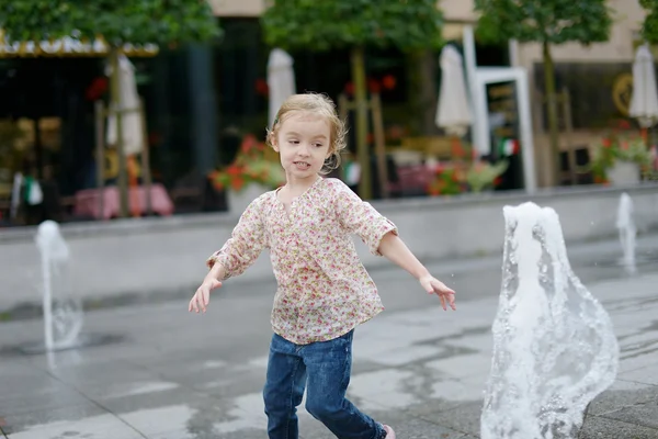 Adorable little girl having fun by a fountain — Stock Photo, Image