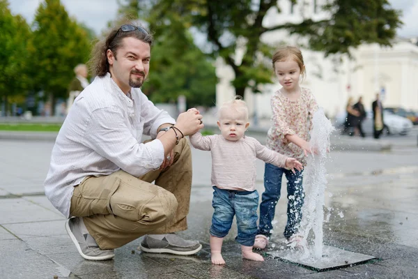 Lyckliga familjen ha roligt av en fontän — Stockfoto