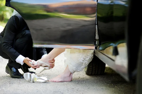 Groom helping bride to put her shoes on — Stock Photo, Image