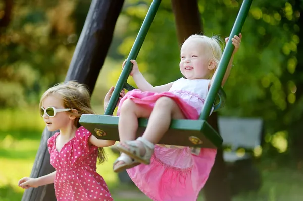 Zwei kleine Schwestern haben Spaß auf einer Schaukel — Stockfoto