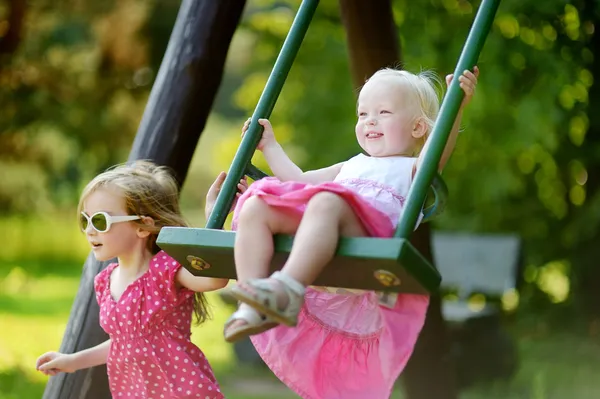 Two little sisters having fun on a swing — Stock Photo, Image