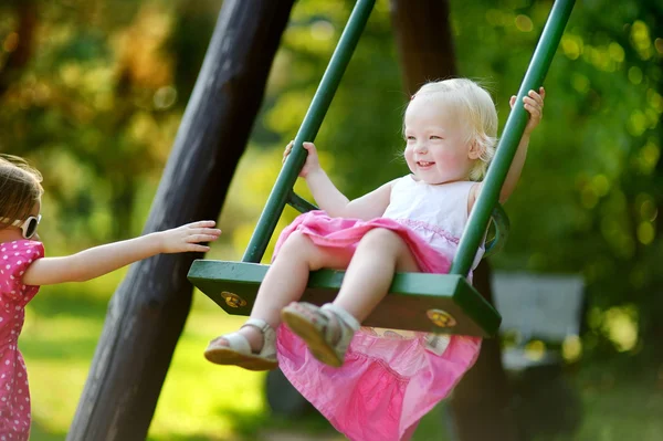 Two little sisters having fun on a swing — Stock Photo, Image