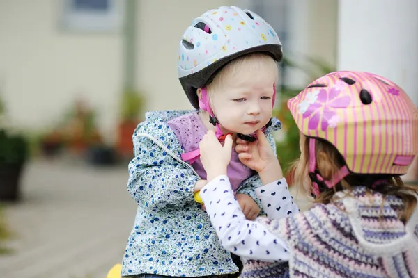 Weinig meisje hepling haar zus te zetten een helm — Stockfoto