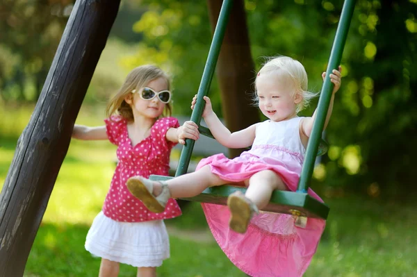 Zwei kleine Schwestern haben Spaß auf einer Schaukel — Stockfoto