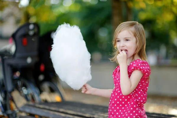 Очаровательная маленькая девочка ест сладкую нить на открытом воздухе — стоковое фото