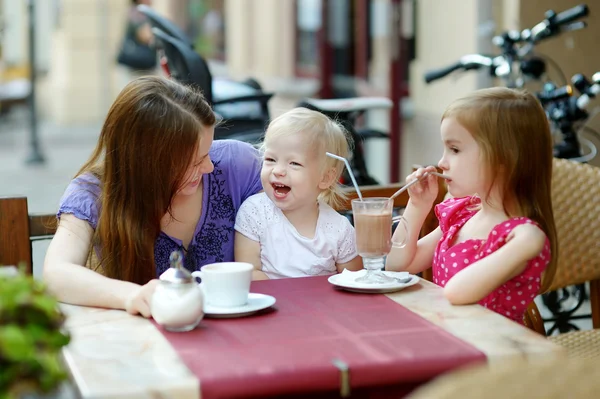 Мать и ее дочери отдыхают в кафе на открытом воздухе — стоковое фото