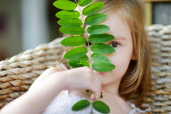 Adorable niña escondida detrás de una hoja — Foto de Stock