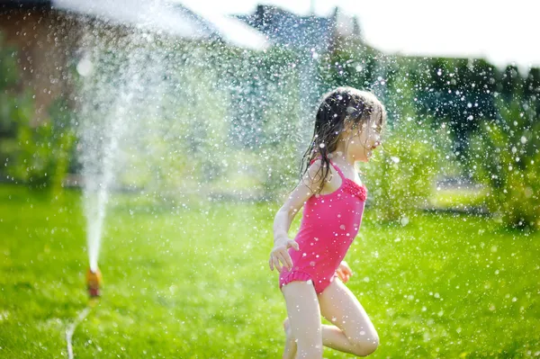 Girl running though a sprinkler — Stock Photo, Image