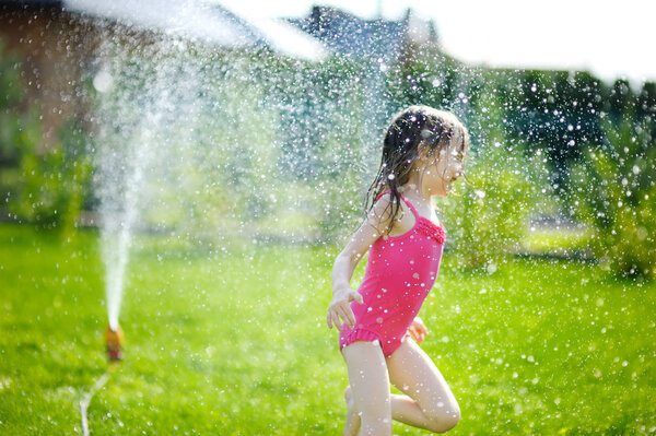 Girl running though a sprinkler