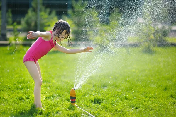 Lány fut bár a sprinkler — Stock Fotó