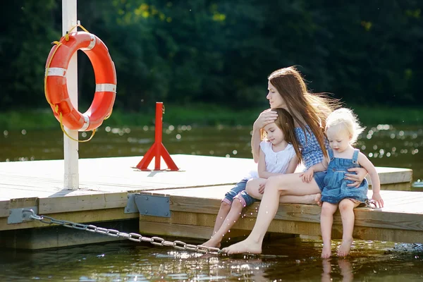 Mother and her children sitting on a wooden pier — Stock Photo, Image