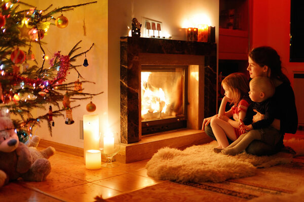 Young mother and her daughters by a fireplace