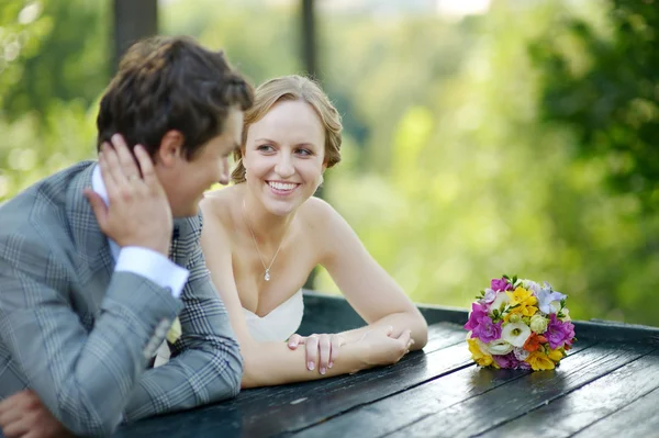 Bride and groom sitting at an outdoor cafe — Stock Photo, Image