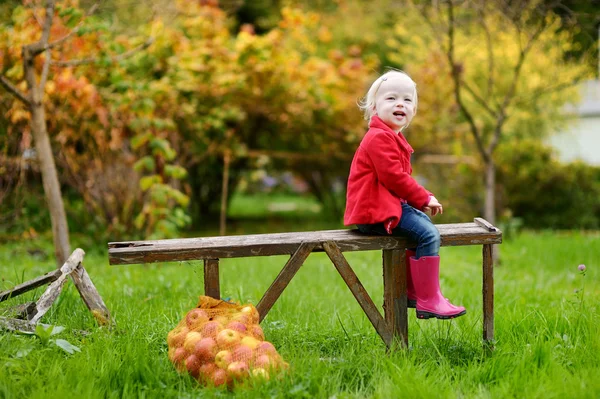 Dziewczynka siedzi na ławeczce, drewniane, na jesień — Zdjęcie stockowe