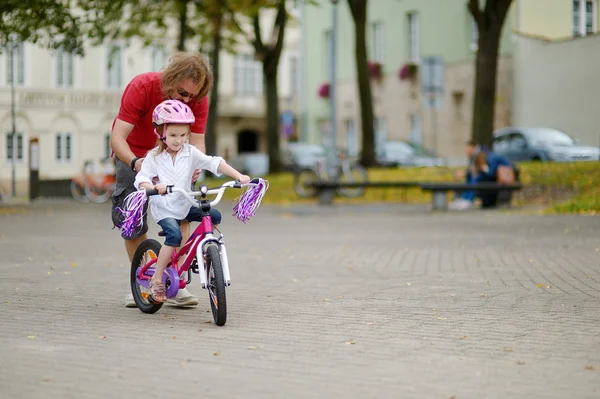 Un père qui apprend à sa fille à faire du vélo — Photo