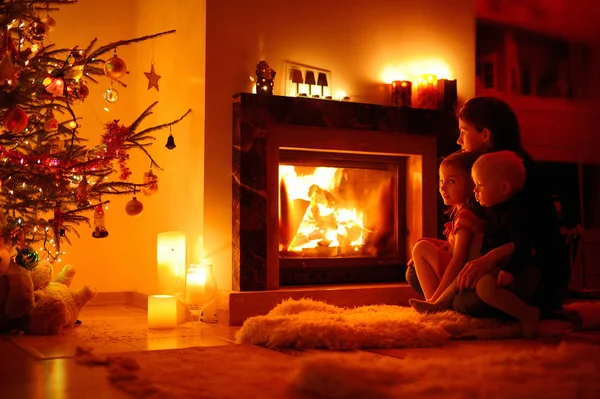 Young mother and her daughters by a fireplace — Stock Photo, Image