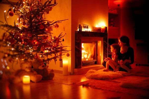 Junge Mutter und ihre Töchter am Kamin — Stockfoto