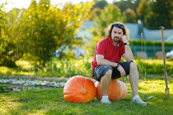 Mladý muž sedí na obrovské dýně — Stock fotografie