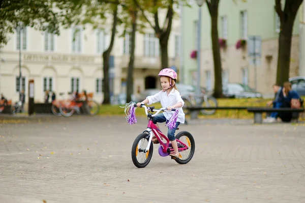 Niña montando una bicicleta en una ciudad — Foto de Stock
