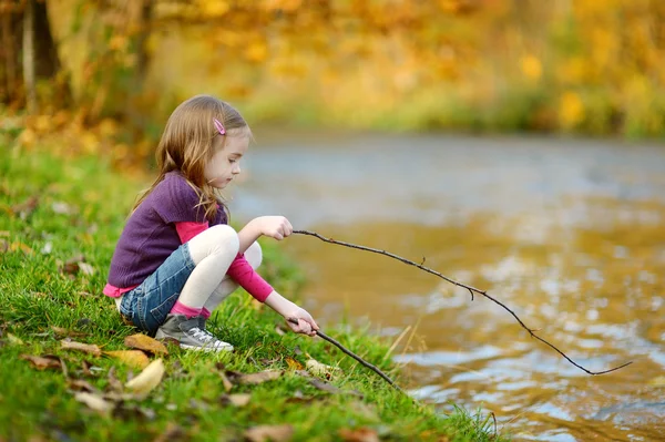 Entzückendes kleines Mädchen, das an einem Fluss spielt — Stockfoto