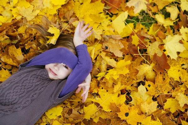 Gadis kecil yang manis berbaring di daun maple emas — Stok Foto