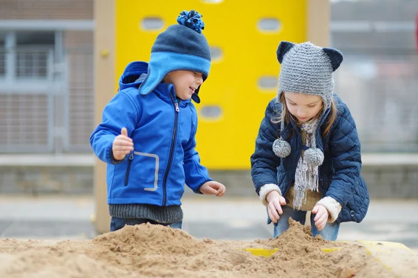 Due bambini che giocano in una sabbiera — Foto Stock