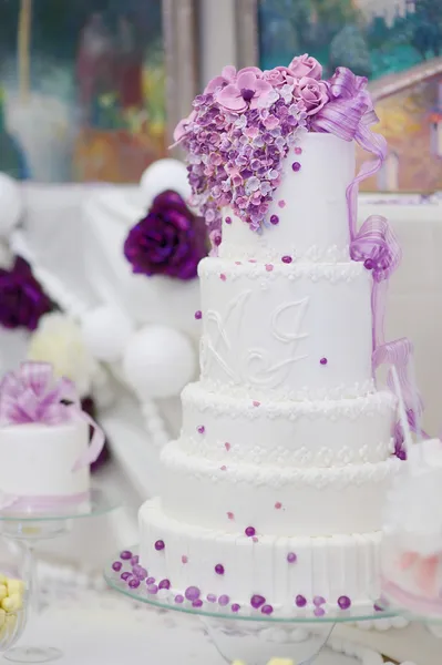 Weiße Hochzeitstorte mit lila Blumen dekoriert — Stockfoto