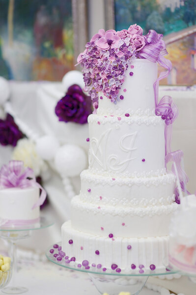 White wedding cake decorated with purple flowers