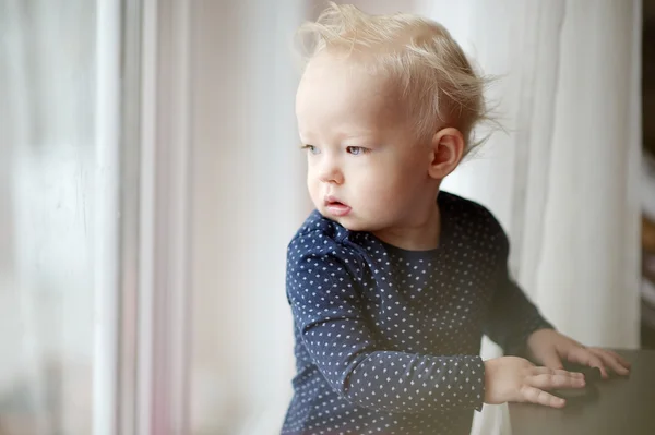 Roztomilé batole dívka při pohledu přes okno — Stock fotografie