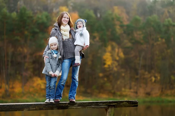 Two little sisters and their mom in autumn park — Stock Photo, Image