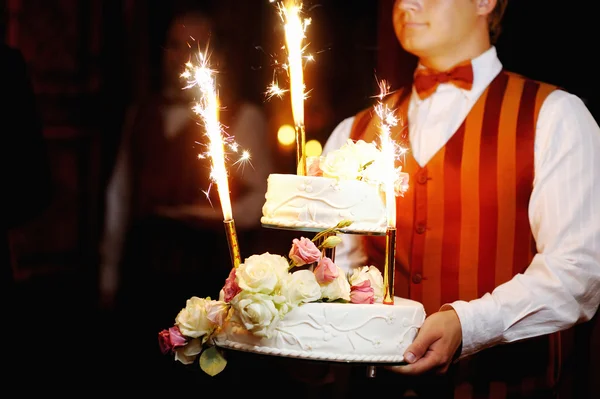 服务员端着在一个黑暗的婚礼蛋糕 — 图库照片