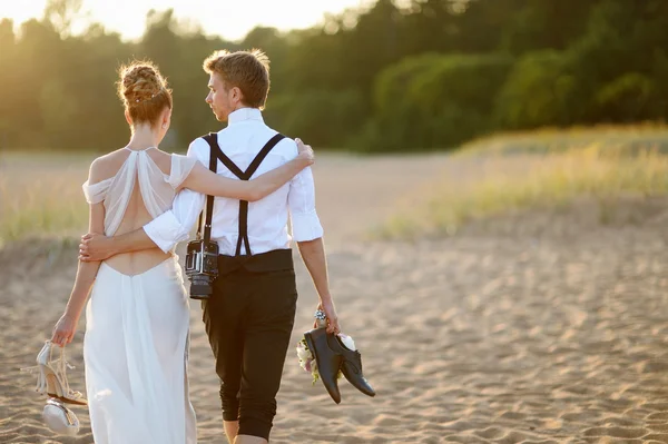 Sposa e sposo su una spiaggia al tramonto — Foto Stock