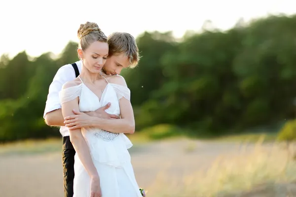 Novia y novio en una playa al atardecer — Foto de Stock