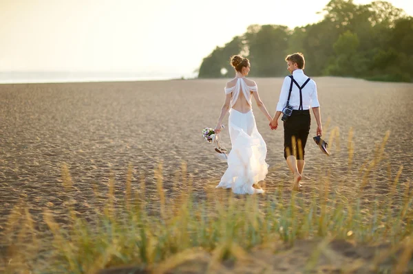 Braut und Bräutigam am Strand bei Sonnenuntergang — Stockfoto