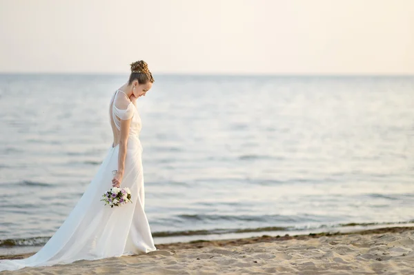 沿着海岸走在夕阳中的新娘 — 图库照片
