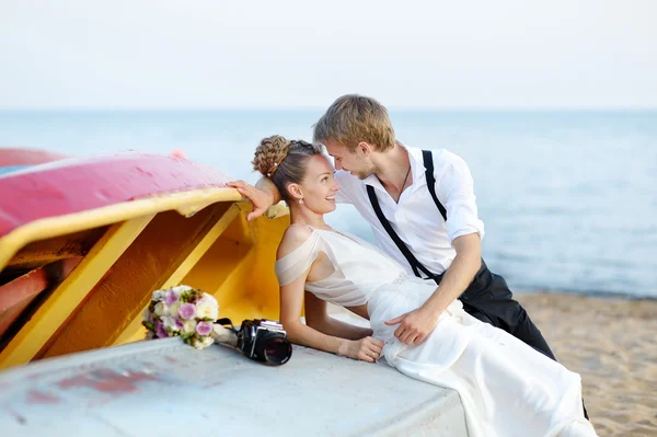 Bruden och brudgummen kramas på en strand — Stockfoto