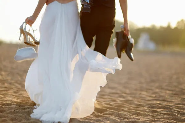 Noiva e noivo em uma praia ao pôr do sol — Fotografia de Stock