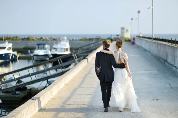 Счастливые жених и невеста идут по пирсу — стоковое фото