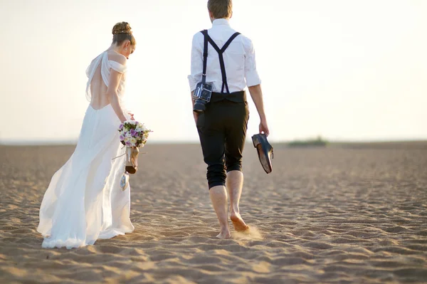 Menyasszony és a vőlegény a tengerparton naplementekor — Stock Fotó