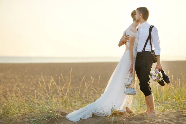 Novia y novio en una playa al atardecer —  Fotos de Stock