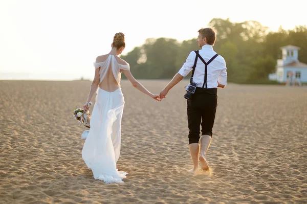 Bruid en bruidegom op een strand bij zonsondergang — Stockfoto