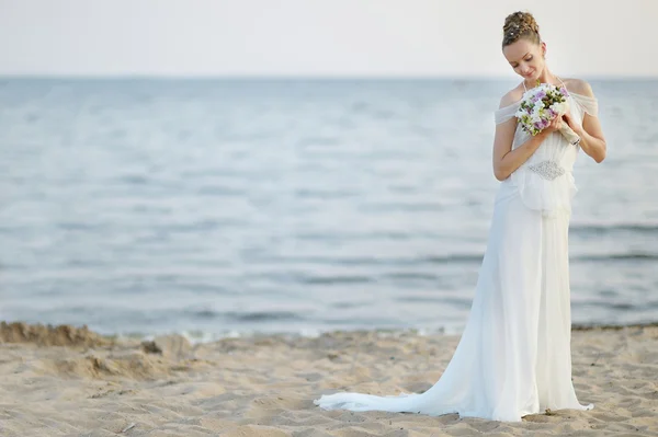 Mariée marchant le long de la côte sur le coucher du soleil — Photo