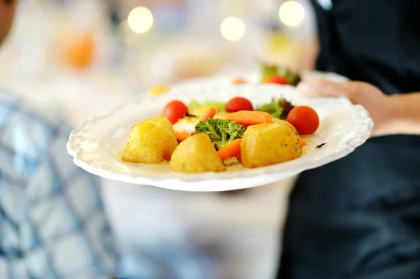 Camarera llevando un plato con plato vegetariano — Foto de Stock