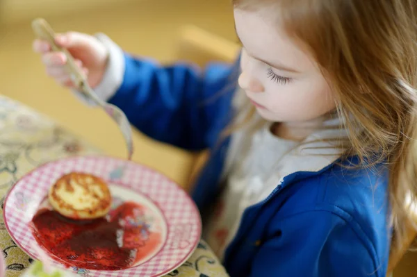 Söt liten flicka äta pannkakor med sylt — Stockfoto