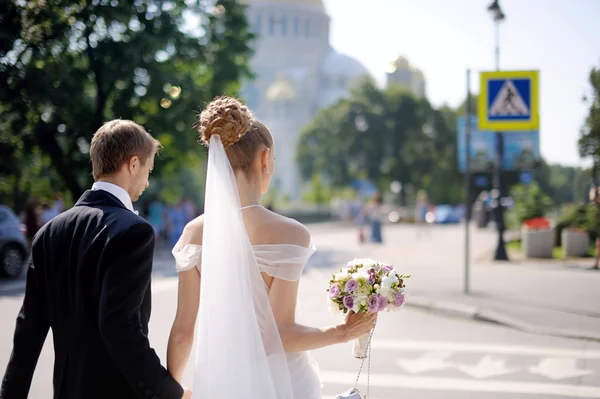 Bride and groom walking across the street Stock Image