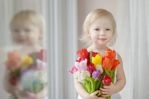 Adorabile bambina con i tulipani vicino alla finestra — Foto Stock