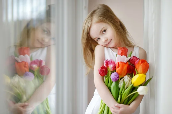 Rozkošná holčička s tulipány oknem — Stock fotografie