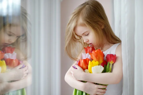 Adorabile bambina con i tulipani dalla finestra — Foto Stock