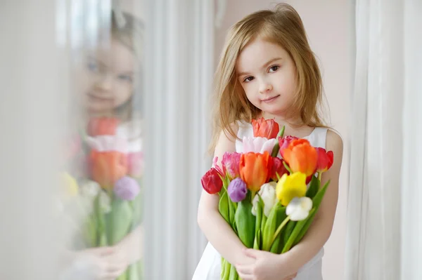 Urocze dziewczynki z tulipany przez okno — Zdjęcie stockowe