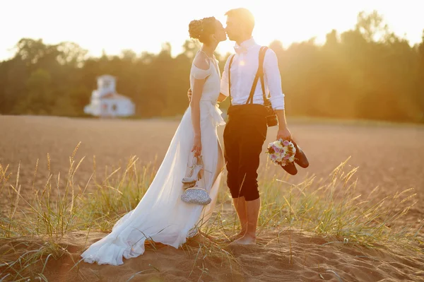 Nevěsta a ženich na pláži při západu slunce — Stock fotografie